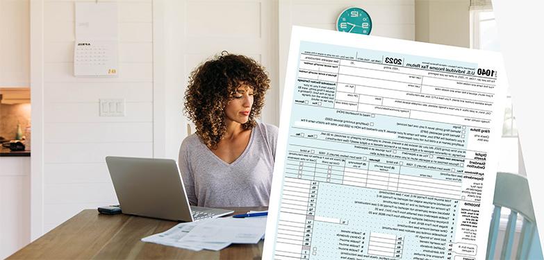 Woman doing taxes with computer, IRS form 1040, and USPS Priority Mail envelope.